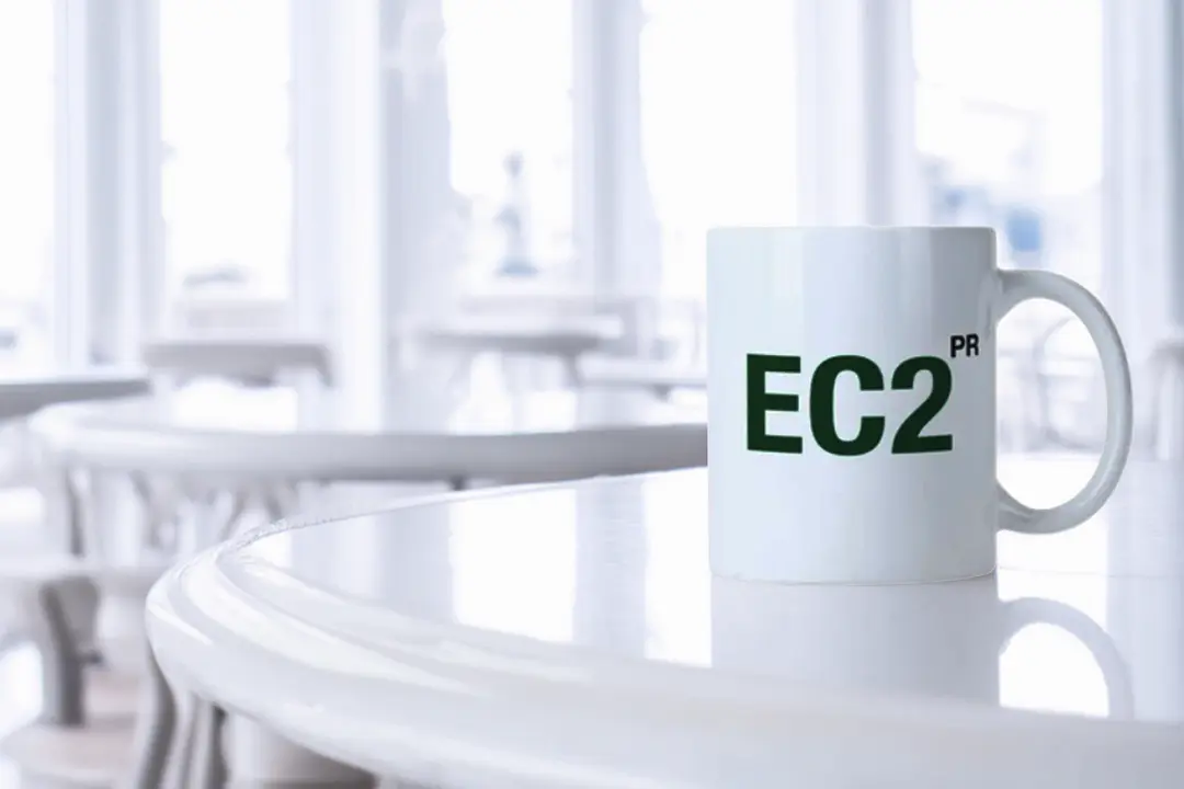 An EC2PR-branded white coffee mug on a white table